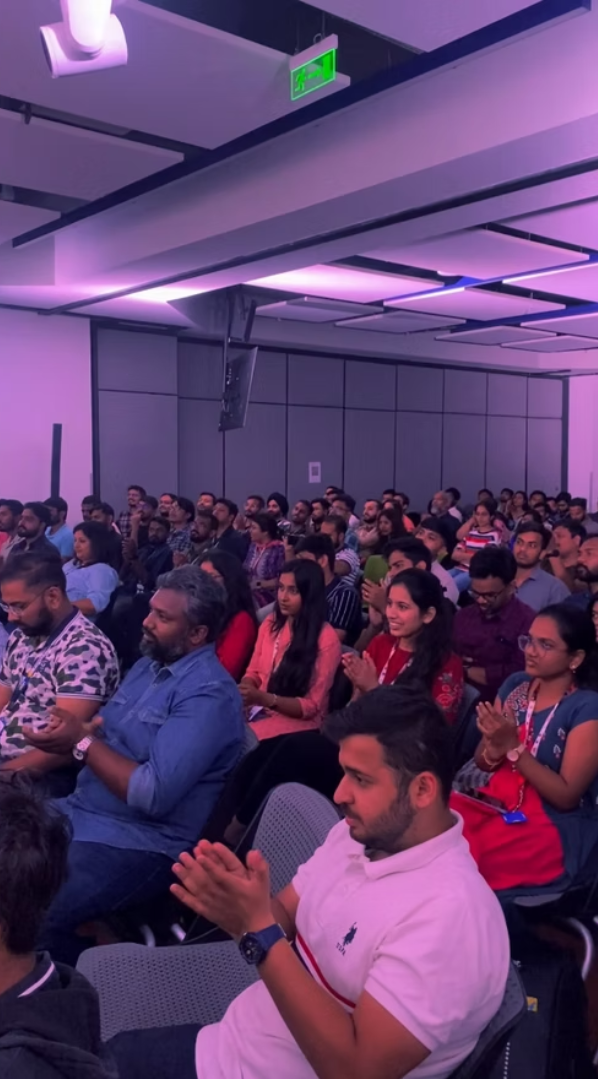 Audience clapping in a purple-lit conference hall