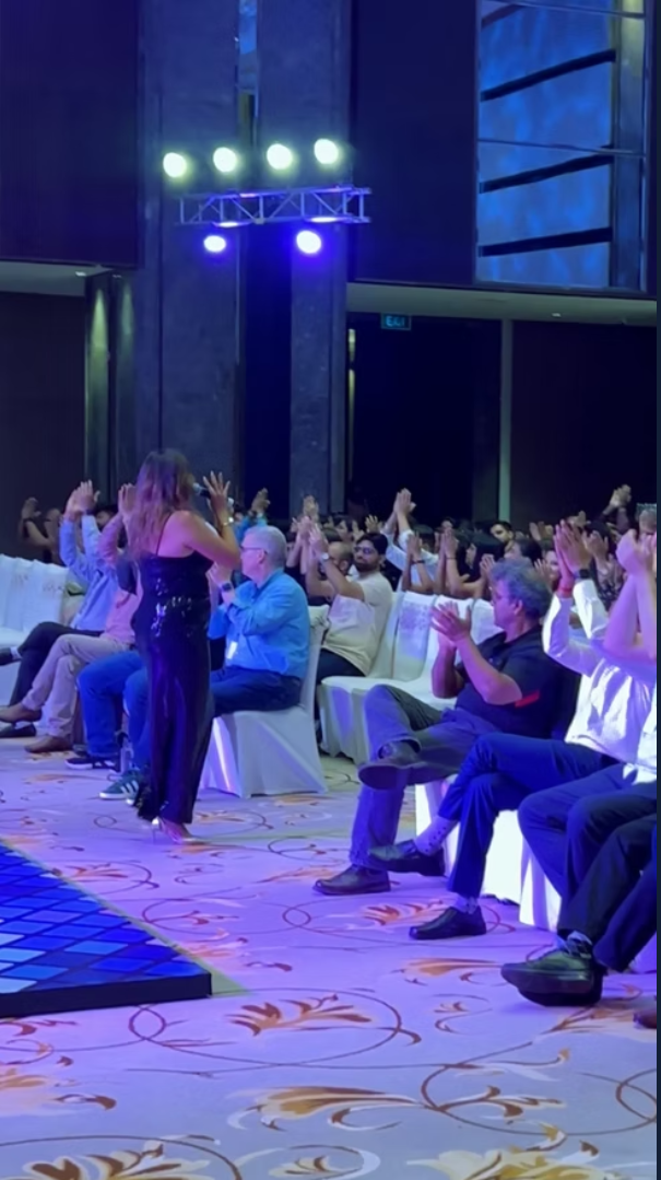 Performer on stage with a clapping seated audience